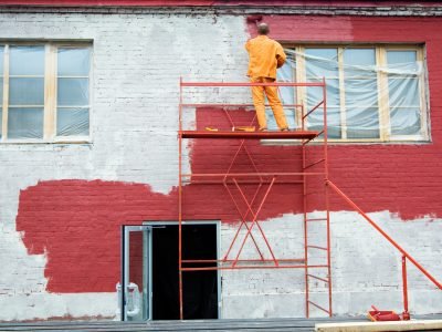 Painting in red Man painting a brick wall in red
